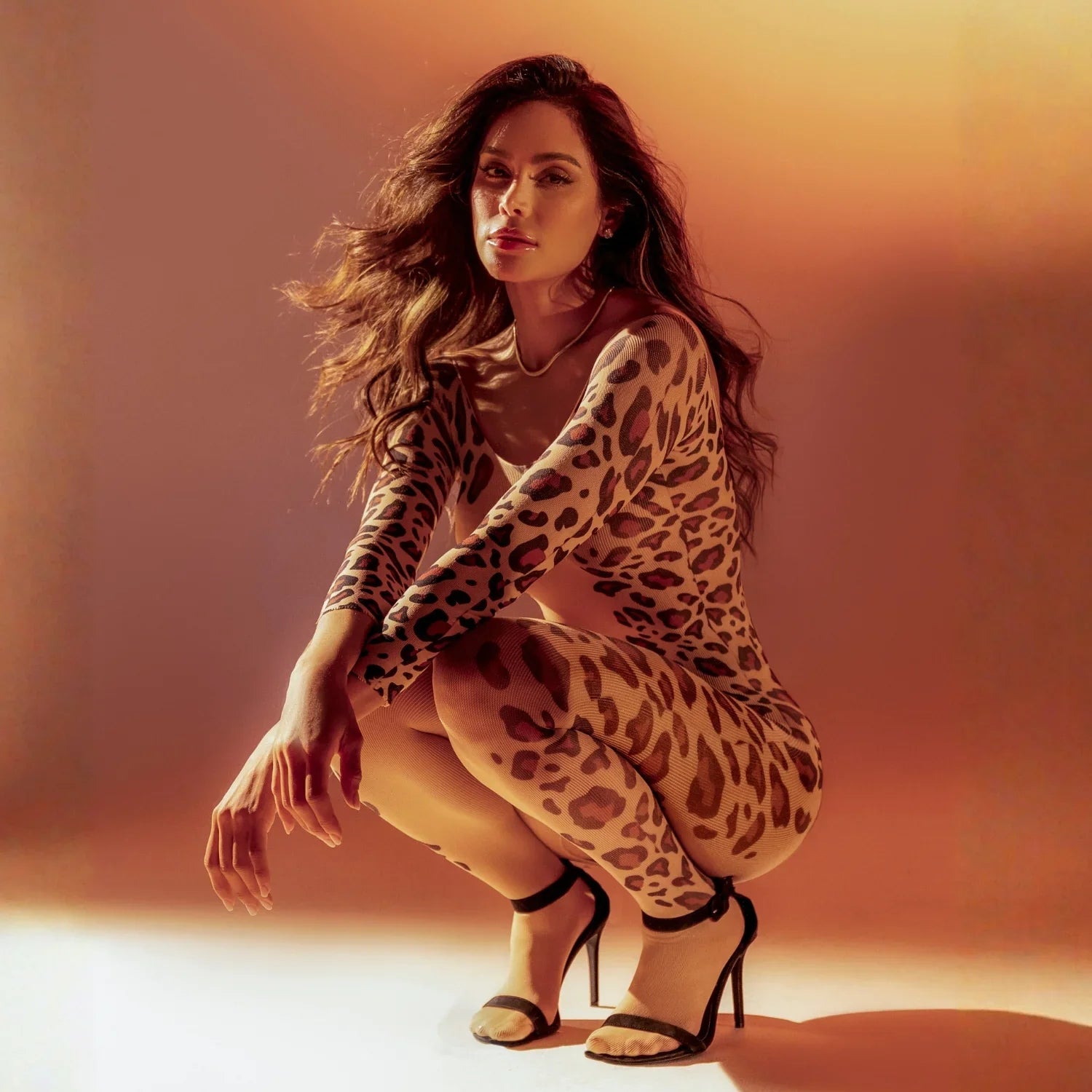 Femme en lingerie une-pièce imprimé léopard, talons hauts, pose élégante, lumière dorée